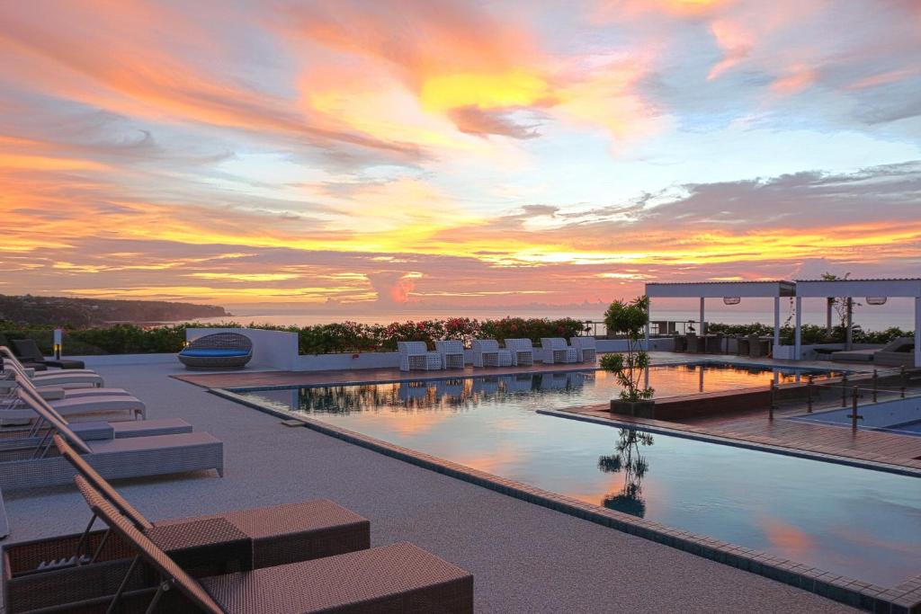 una piscina en la parte superior de un edificio con puesta de sol en Klapa Resort, en Uluwatu