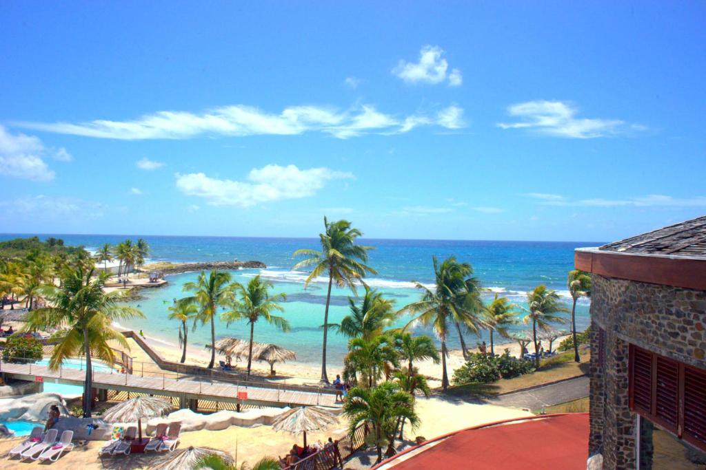 uma vista para a praia a partir da varanda de um resort em Studio Manganao Saint François Piscine & Plage em Saint-François