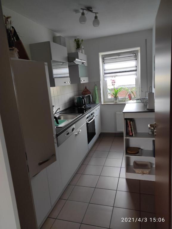 uma pequena cozinha com electrodomésticos brancos e uma janela em Leineblick em Seelze