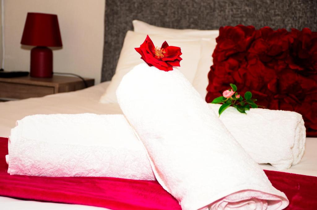 a bed with white towels and a red flower on it at Novus Guest House in Pretoria