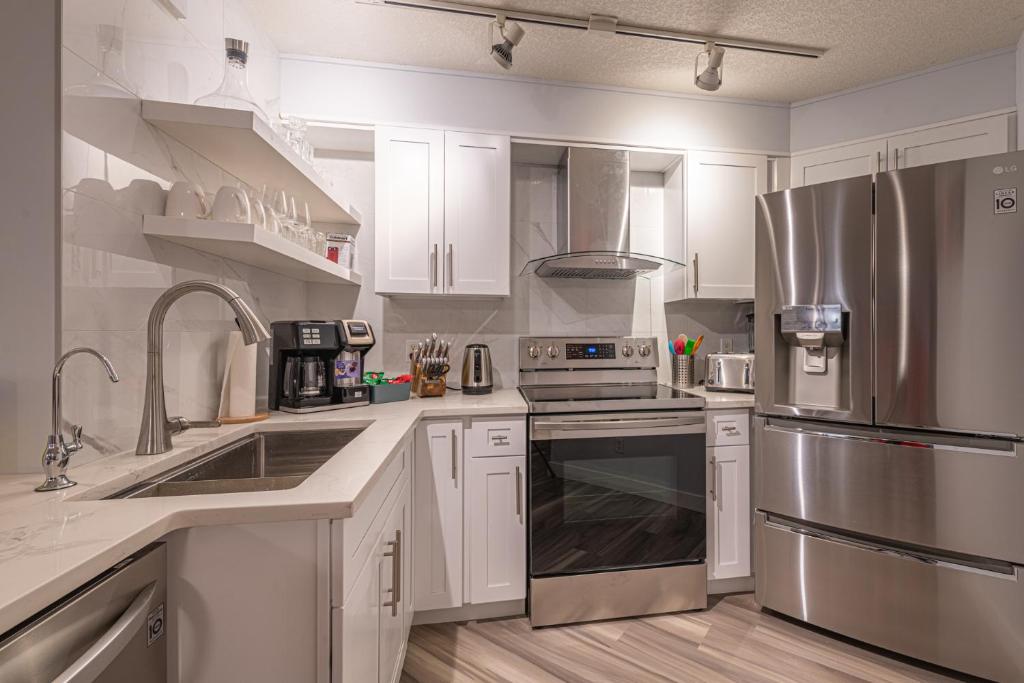 kuchnia z białymi szafkami i urządzeniami ze stali nierdzewnej w obiekcie Luxurious One Bedroom Suite for a Larger Family 162 w mieście Canmore