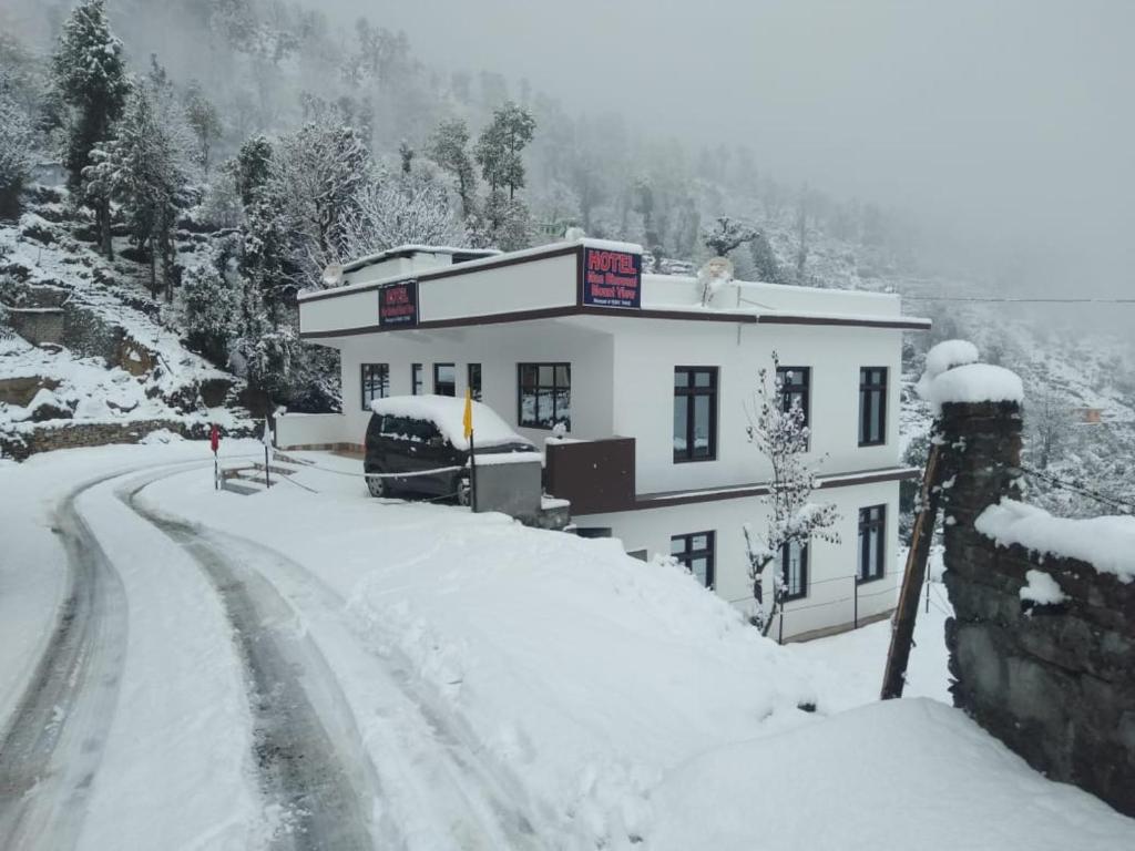 un edificio cubierto de nieve en una carretera cubierta de nieve en Vamoose Maa Bhawani Munsiyari, en Munsyari