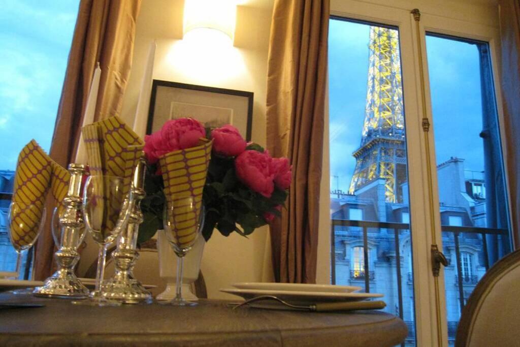 - une table avec des vases de fleurs et une vue sur la tour d'Eiffel dans l'établissement 27 avenue de la bourdonnais 75007 CHABLIS, à Paris