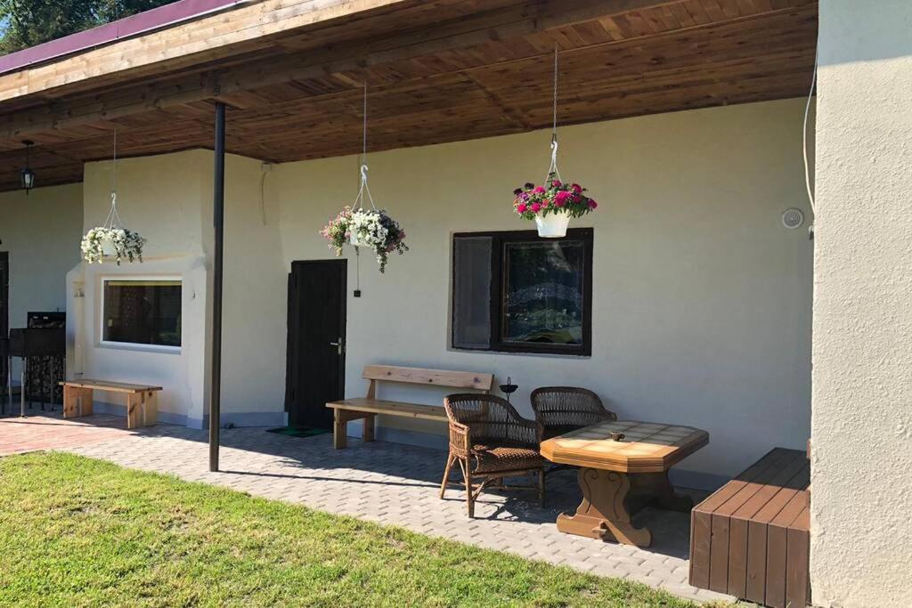 a patio with a table and a bench and flowers at Atpūta pie jūras in Bigauņciems