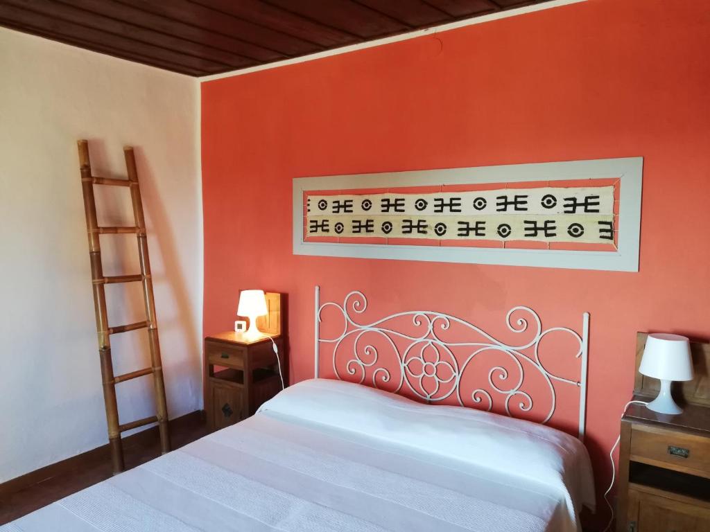 una camera con un letto con una parete arancione di Le civette a Montecatini Val di Cecina