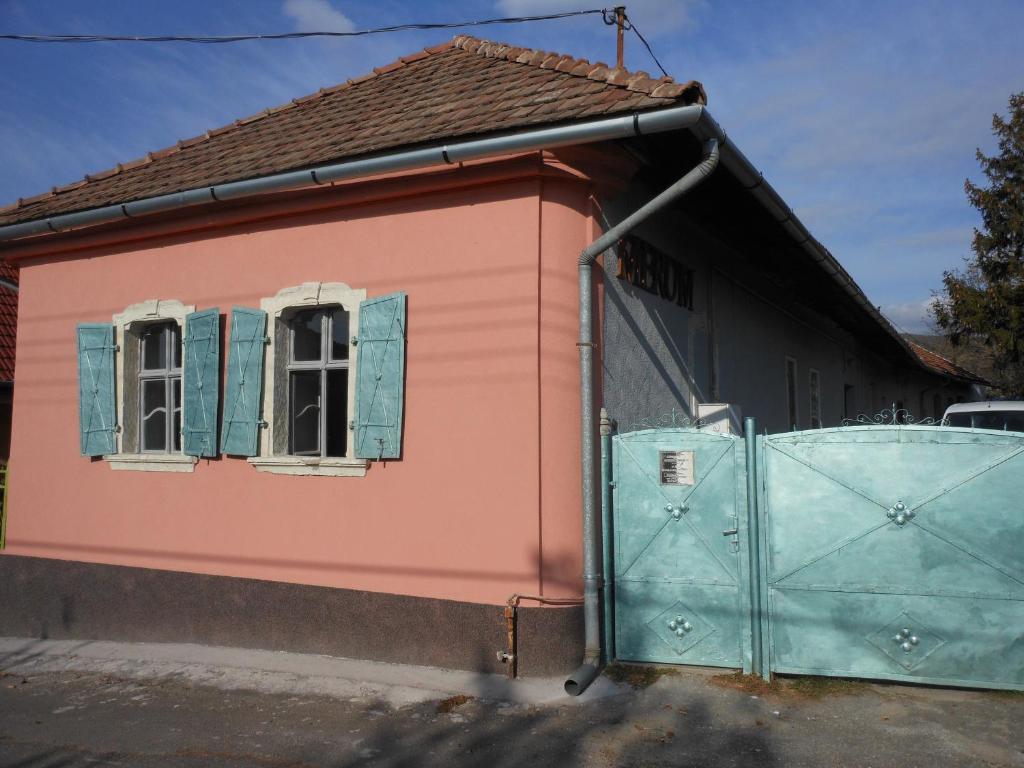 Merum Pincészet és Vendégszoba في Tállya: منزل وردي مع نوافذ زرقاء وبوابة