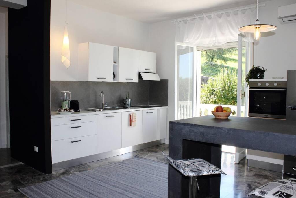 a kitchen with white cabinets and a large window at Casa lu Monaco tranquillità a due passi dal mare in Porto dʼAscoli