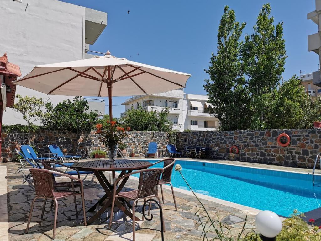 een tafel met een parasol naast een zwembad bij Mark Hotel in Heraklion