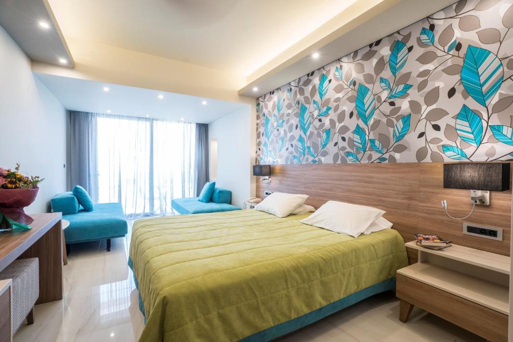 a bedroom with a large bed and blue chairs at Atrion Resort Hotel in Agia Marina Nea Kydonias