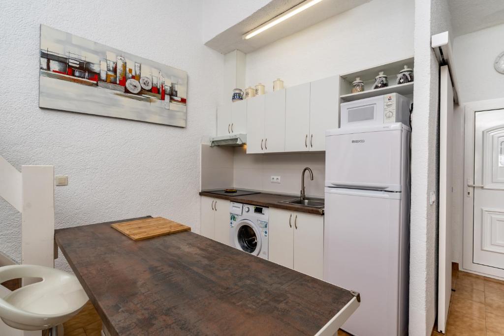a kitchen with a wooden table and a white refrigerator at Solymar in Denia