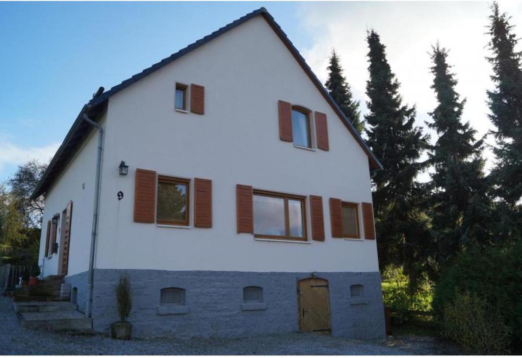 une grande maison blanche avec des fenêtres à volets marron dans l'établissement Landhaus am Diemelsee, à Diemelsee
