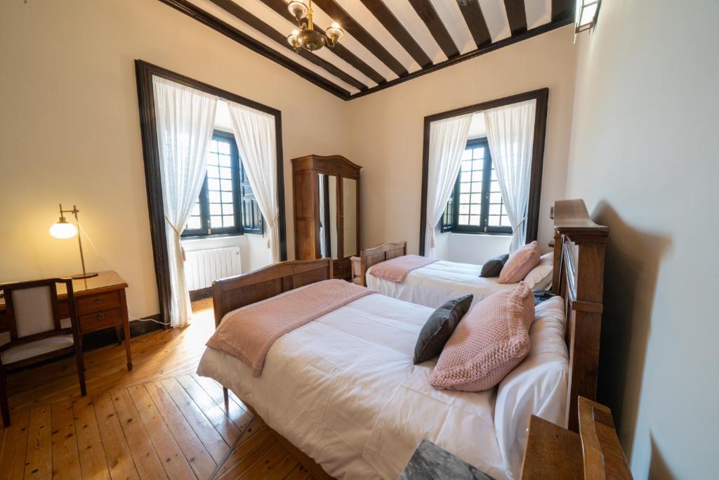 1 dormitorio con 2 camas y 2 ventanas en La Posada de Pradorey, en Ventosilla