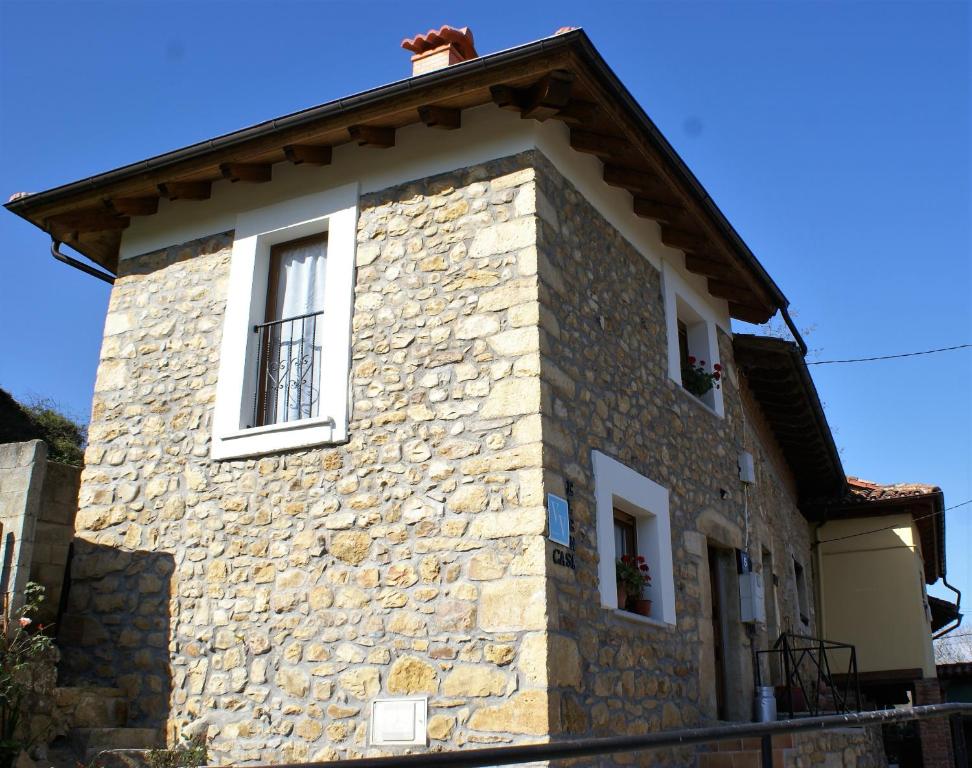 ein Steinhaus mit zwei seitlichen Fenstern in der Unterkunft Casa Elena Cangas de Onis con WiFi y parking gratuito in Cangas de Onís