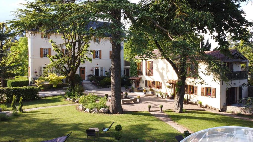 una gran casa blanca con árboles en el patio en Gites du Caylar - Chambres et Appartments en Le Caylar