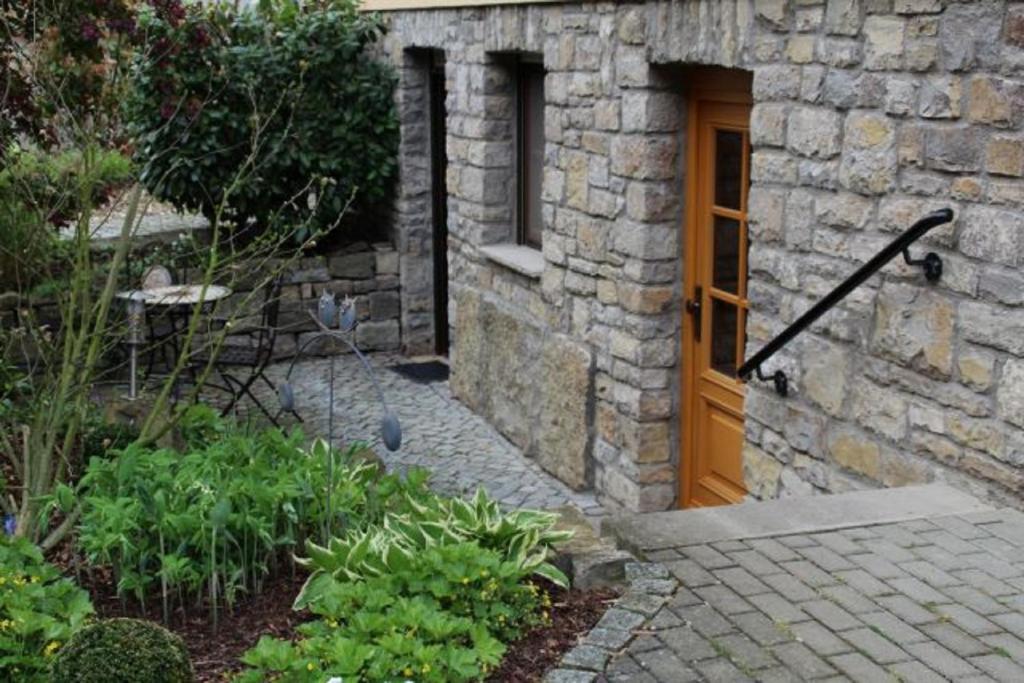 un edificio de piedra con una puerta de madera y algunas plantas en Ferienwohnung - Zimmervermietung Ringelmann, en Dettelbach