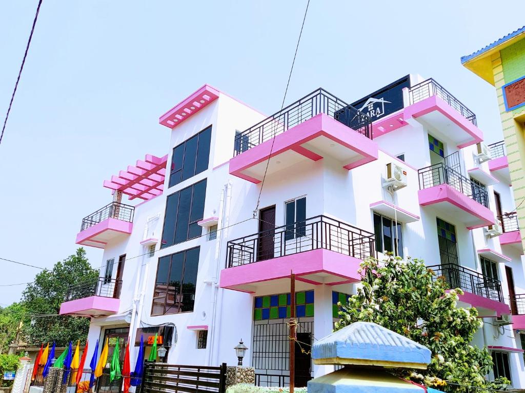 a pink and white building with colorful balconies at Zara Homestay Santiniketan in Shānti Niketan