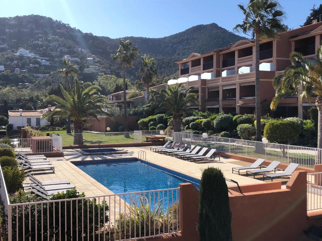 a resort with a swimming pool with lounge chairs and a building at Plage de Miramar in Théoule-sur-Mer