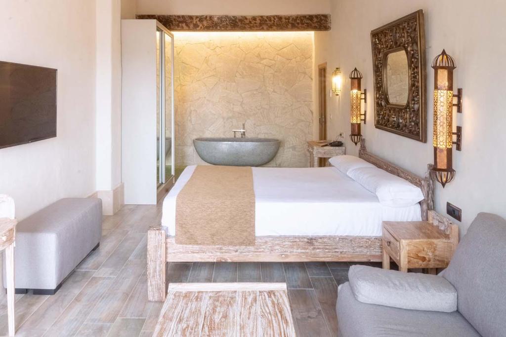 a bedroom with a large bed and a bath tub at El Cortijo de Zahara by QHotels in Zahara de los Atunes