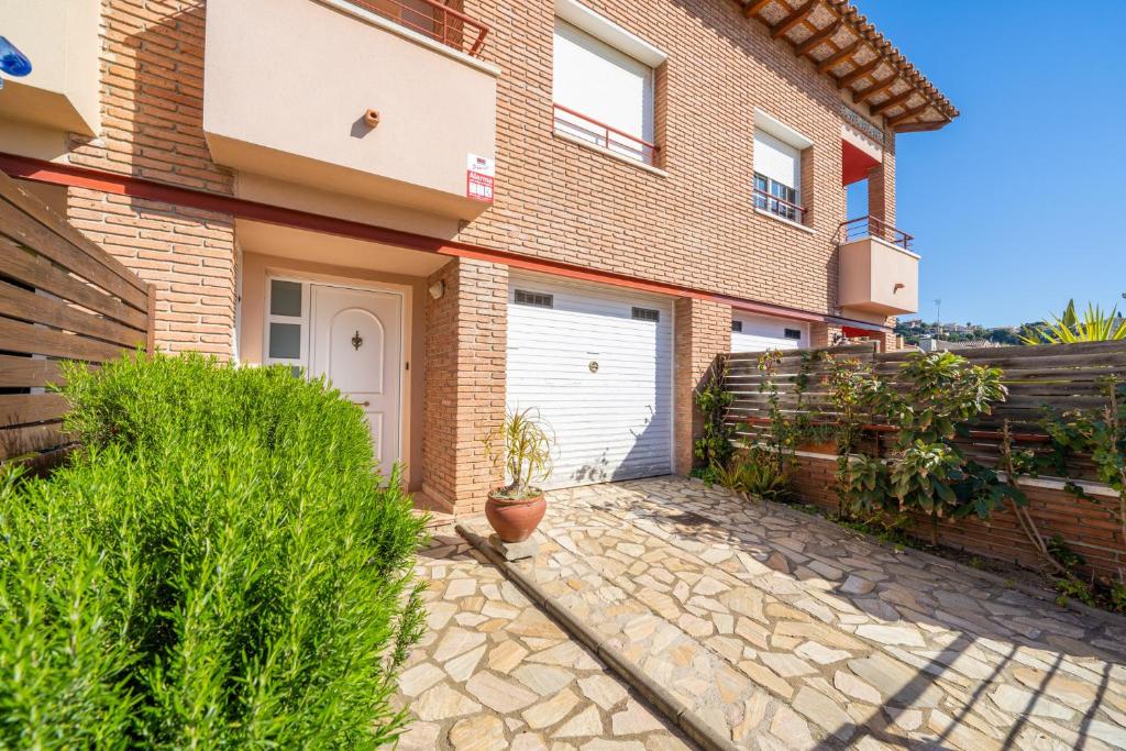 uma casa de tijolos com uma garagem branca em HomeHolidaysRentals Charme - Costa Barcelona em Santa Susanna