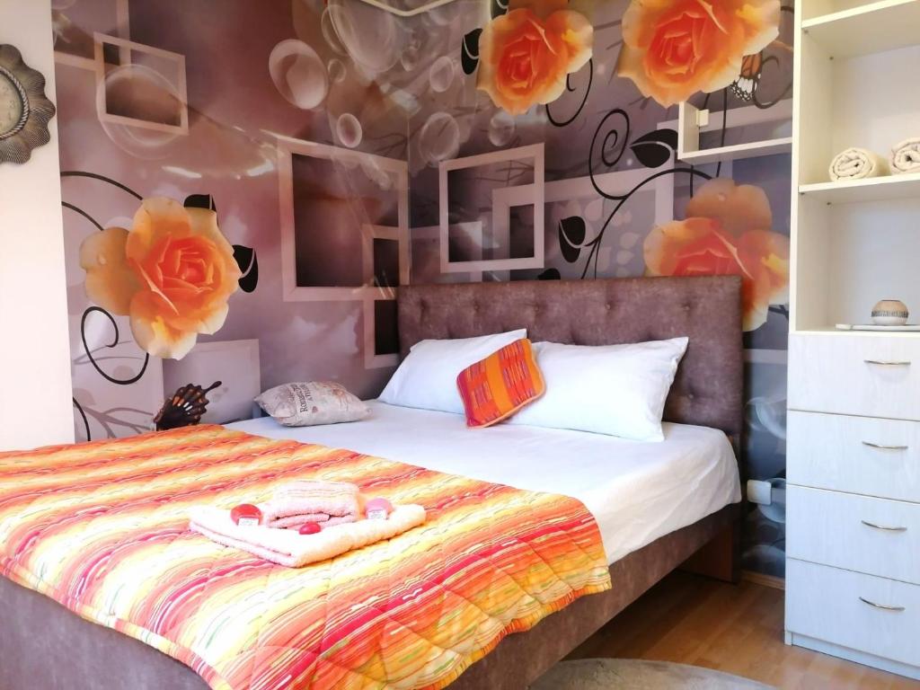 1 dormitorio con 1 cama con flores en la pared en Apartman Slavica en Nova Varoš