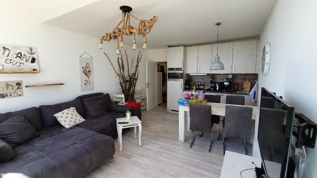 ein Wohnzimmer und eine Küche mit einem Sofa und einem Tisch in der Unterkunft Vier Jahreszeiten Haus 4a Whg 05 in Großenbrode