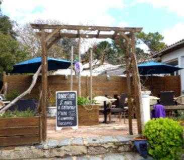 une pergola en bois avec un panneau dans la cour dans l'établissement Résidence Fleur des Pins - Gites & Chambres d'Hôtes, à Saint-Georges-dʼOléron