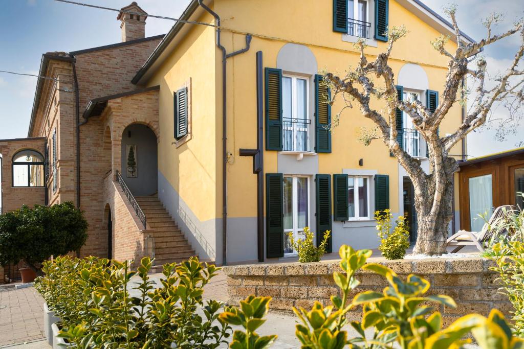 a yellow house with green shutters at La Locanda dei Cavalieri Country House in Civitanova Marche