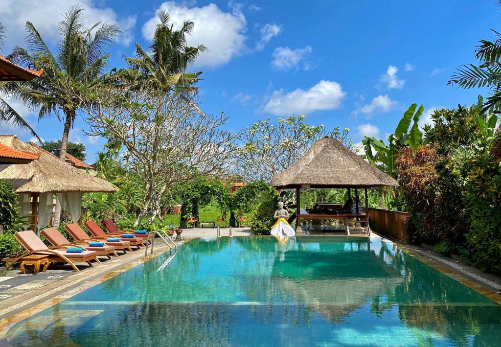 a pool at a resort with chairs and a gazebo at Gayatri in Ubud