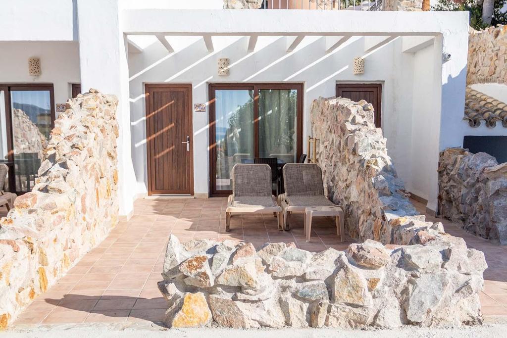 two chairs sitting in front of a building with rocks at El Cortijo de Zahara by QHotels in Zahara de los Atunes