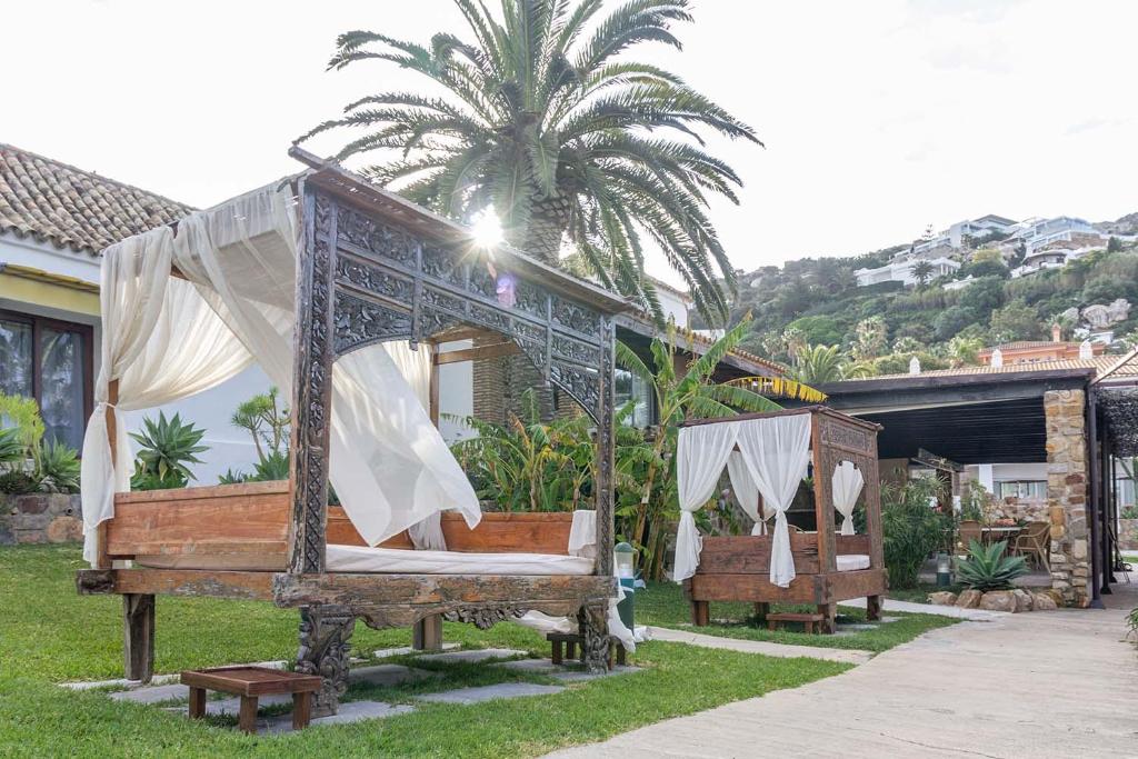 a canopy bed in a yard with a palm tree at El Cortijo de Zahara by QHotels in Zahara de los Atunes
