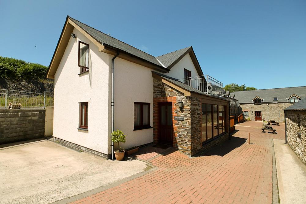 a white house with a brick sidewalk next to a building at The Workshop in Aberystwyth