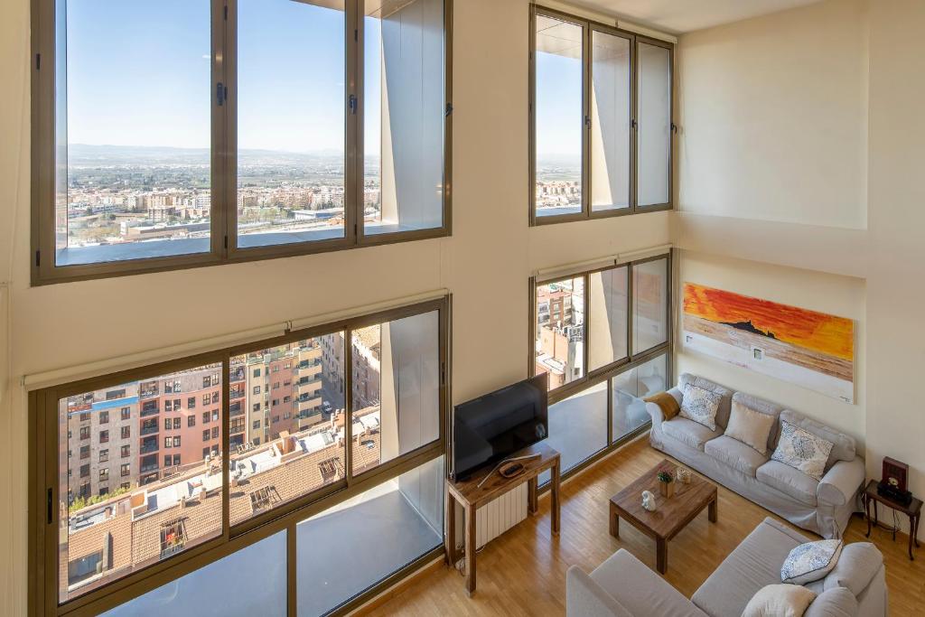 a living room with large windows and a tv at Atico Top Granada, Penthouse, 18-19th floor, City Centre, Views, Terrace, Free Parking in Granada