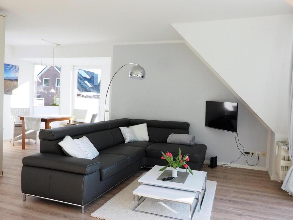 ein Wohnzimmer mit einem schwarzen Sofa und einem Tisch in der Unterkunft Appartement Silbermöve AMH/002 in Scharbeutz