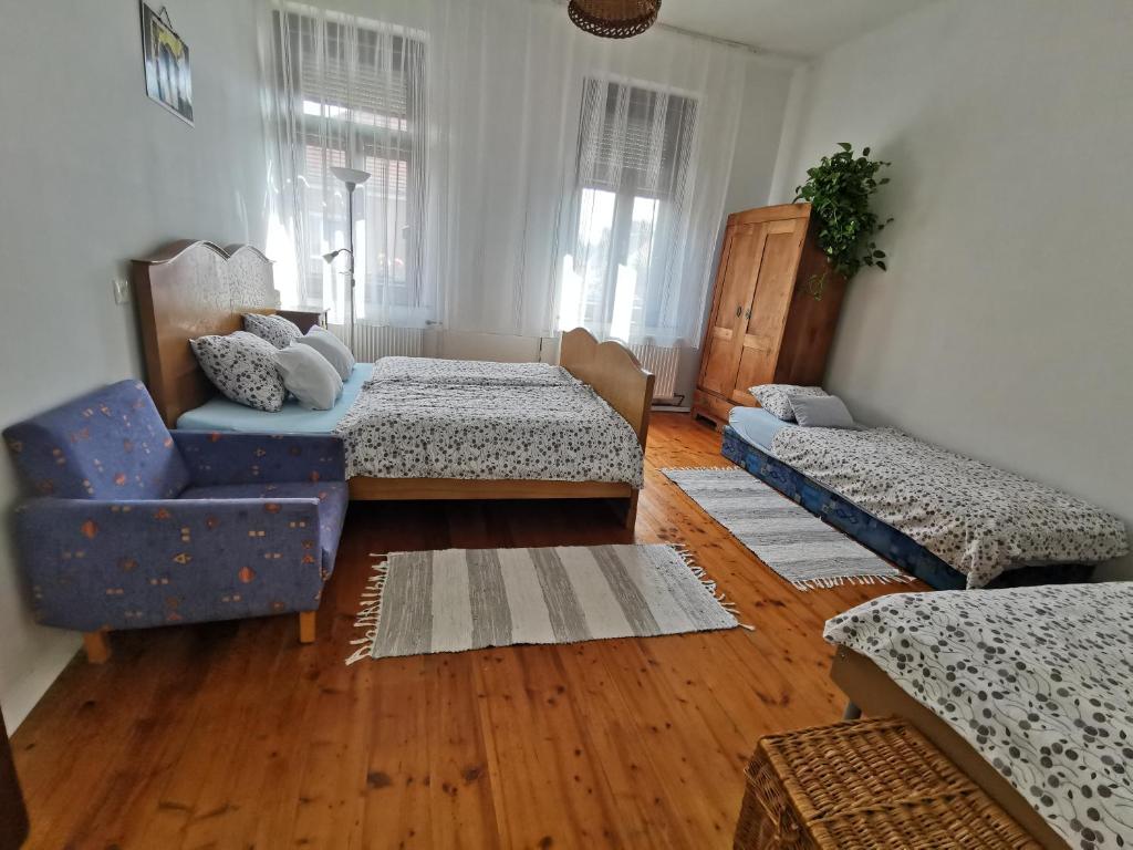 uma sala de estar com 2 camas e uma cadeira azul em Green Garden House em Gencsapáti