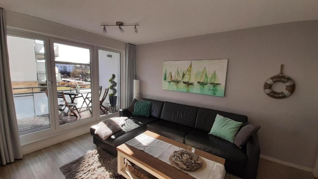 uma sala de estar com um sofá preto e uma mesa em App-Waterkant-STR-10A em Scharbeutz