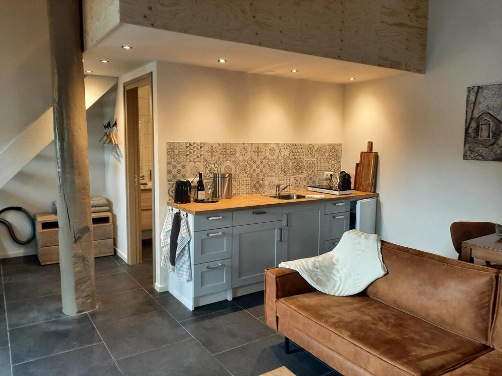 a kitchen with a counter and a couch in a room at Appartementen Hoek 1 in Baflo