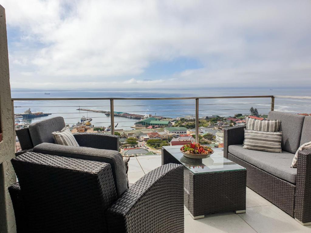 balcón con sillas de mimbre y vistas al océano en 3ColoursBlue Guest House, en Mossel Bay