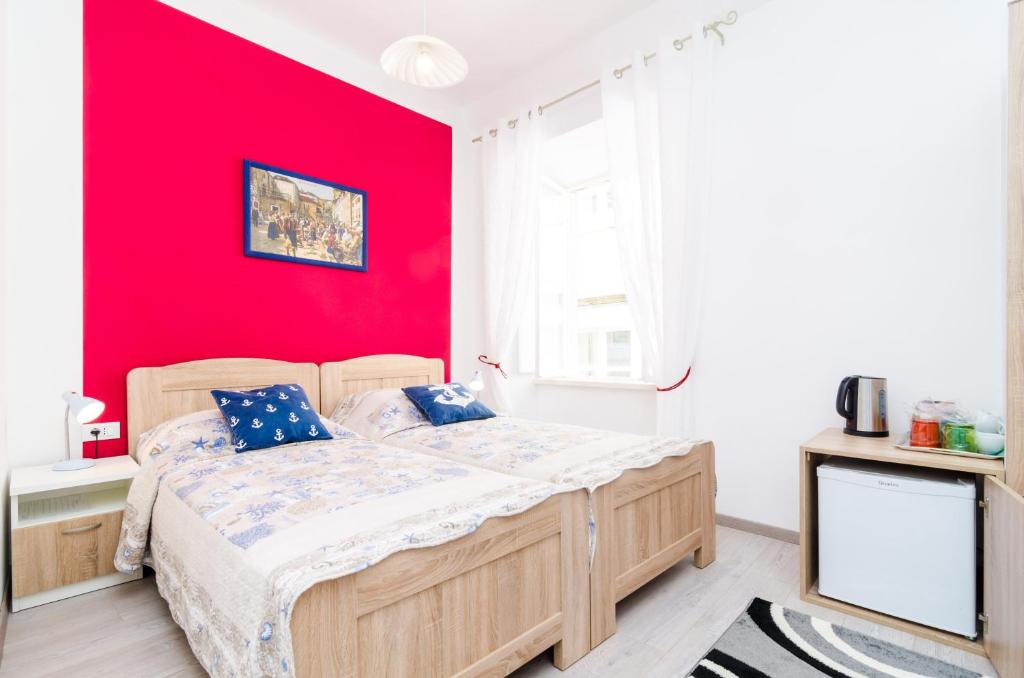 a bedroom with a bed with a red wall at Rooms Tezoro in Dubrovnik