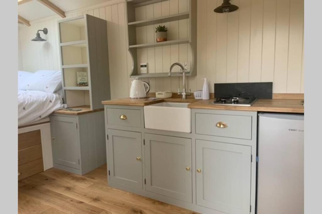 a kitchen with white cabinets and a sink at Trevone Luxury Shepherds hut close to the beach in Saint Merryn
