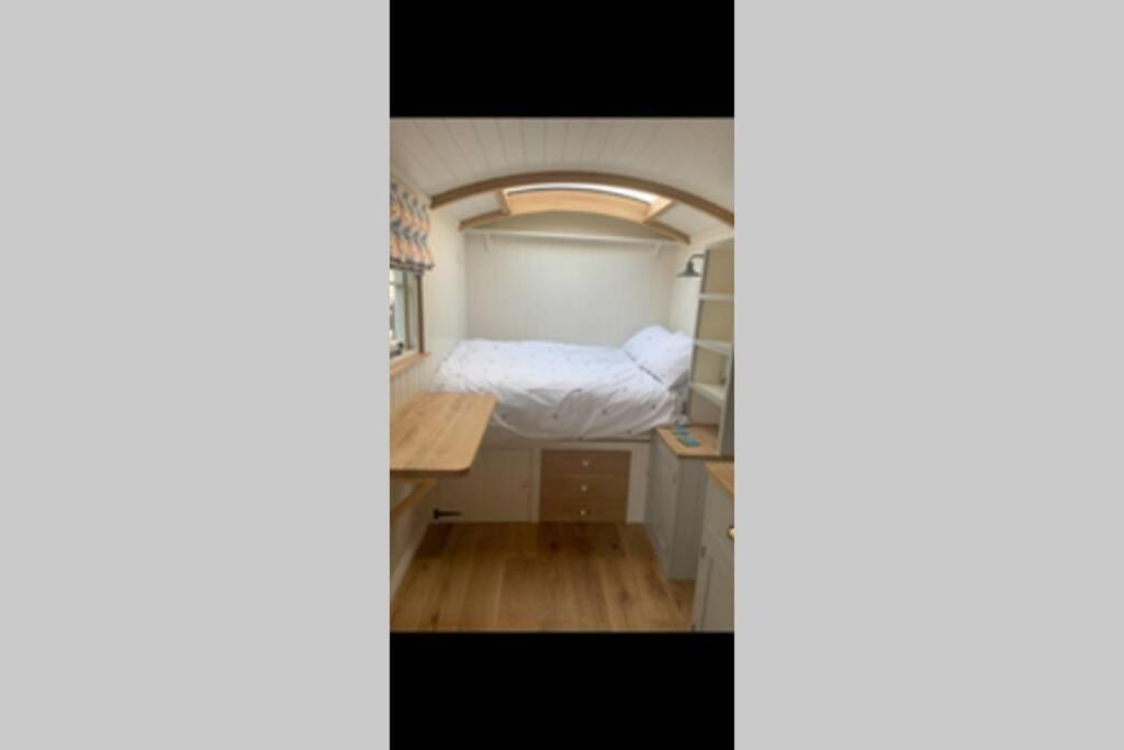 a small bedroom with a bed and a desk at Trevone Luxury Shepherds hut close to the beach in Saint Merryn