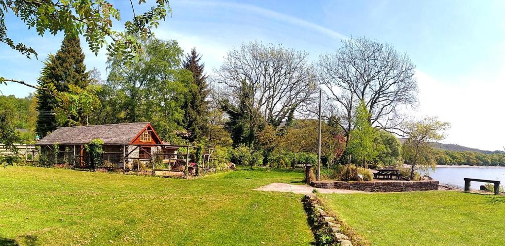 ein Park mit einem Haus und einem Spielplatz neben einem See in der Unterkunft Loch Lomond shore Boat House in Balmaha