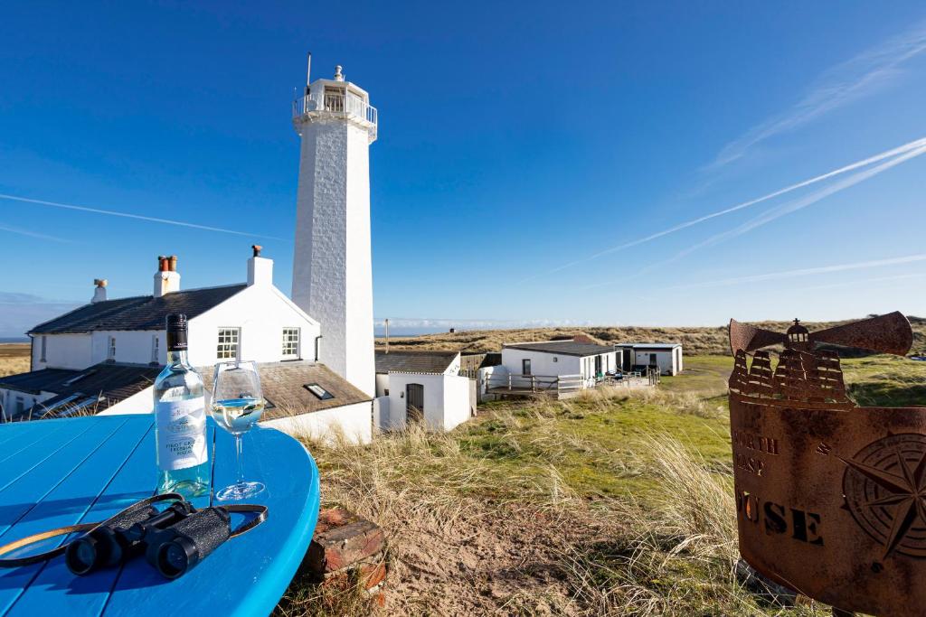 a table with a glass of wine and a lighthouse at Finest Retreats - Lighthouse Cottage in Rampside