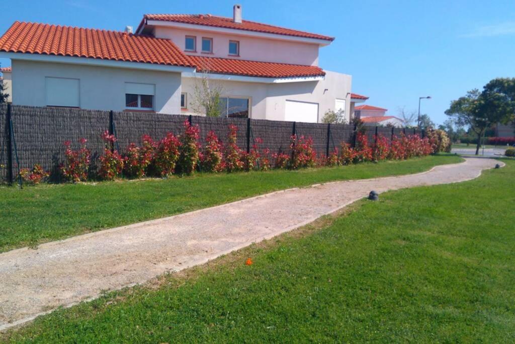 a fence in front of a house with red flowers at Cocooning in Torreilles