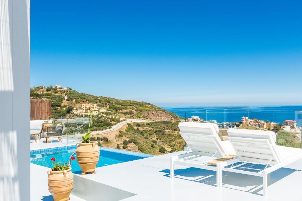 a view of a swimming pool and two white chairs at Royal Garden Villas in Balíon