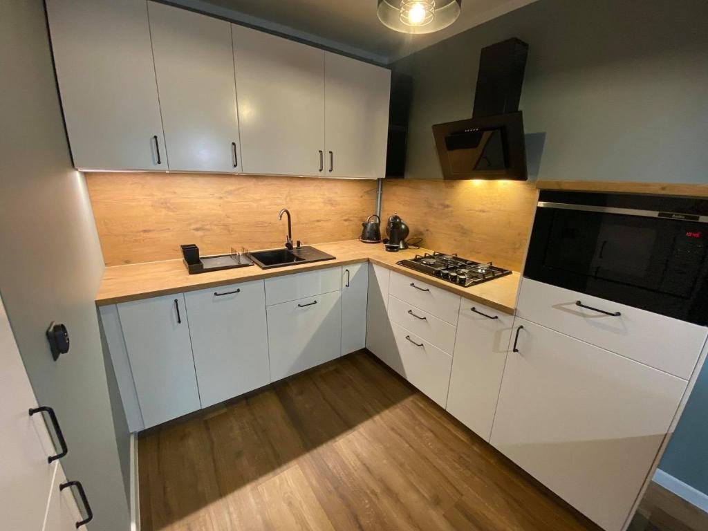 uma cozinha com armários brancos, um lavatório e um fogão em Apartament Wiosełko Warszawa em Varósvia