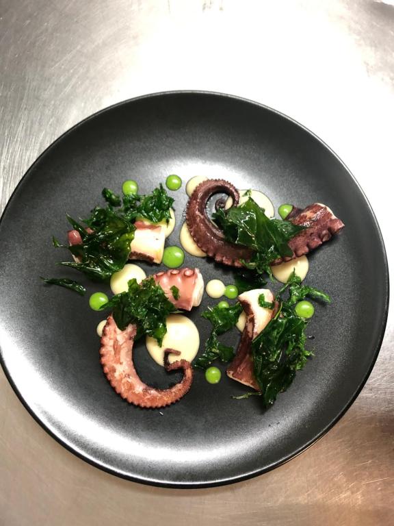 a black plate of food with meat and greens at Luna Convento Copanello B&B in Stalettì