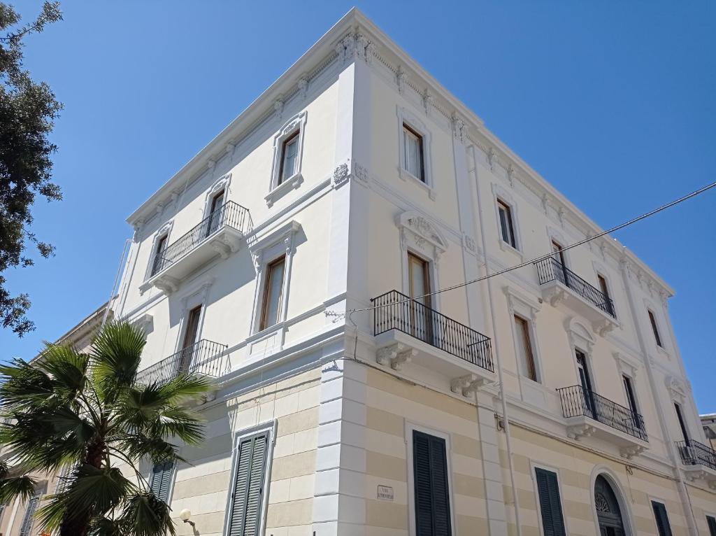 biały budynek z balkonem i palmą w obiekcie iLCastellano - Suites & Apartments w mieście Lecce