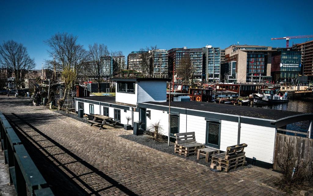 ein Gebäude mit Bänken neben einem Fluss mit Gebäuden in der Unterkunft Houseboat Amsterdam in Amsterdam