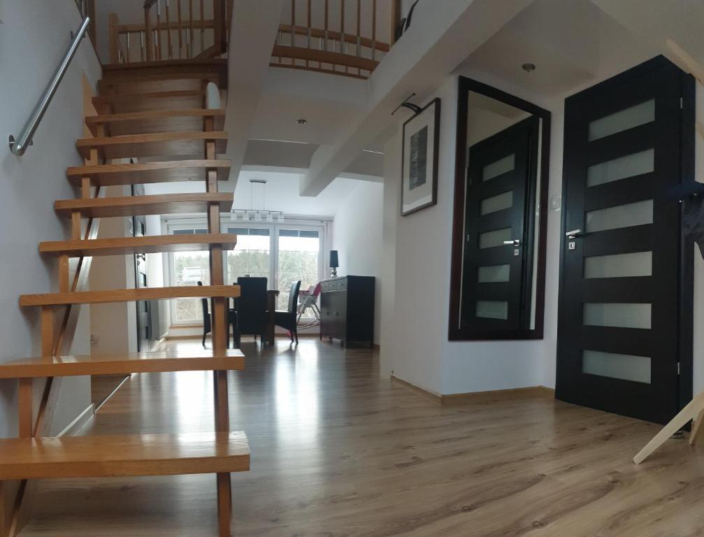 a living room with a wooden staircase in a house at Apartament Stara Leśniczówka in Polnica