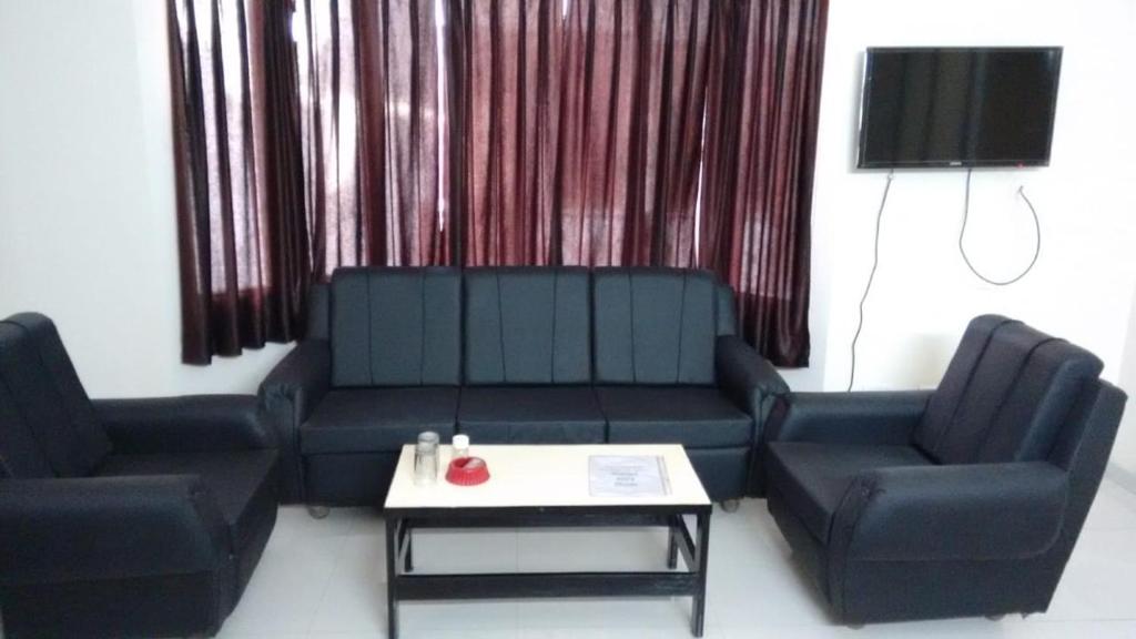 uma sala de estar com um sofá e duas cadeiras e uma mesa em Vamoose Park Palace em Bharatpur